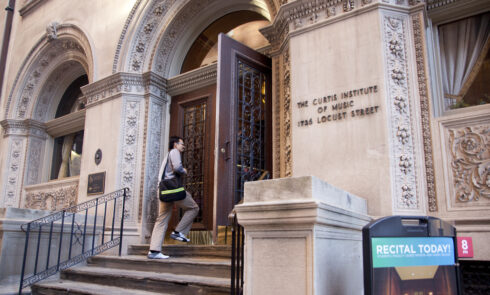 A student walks up the steps to a university building.
