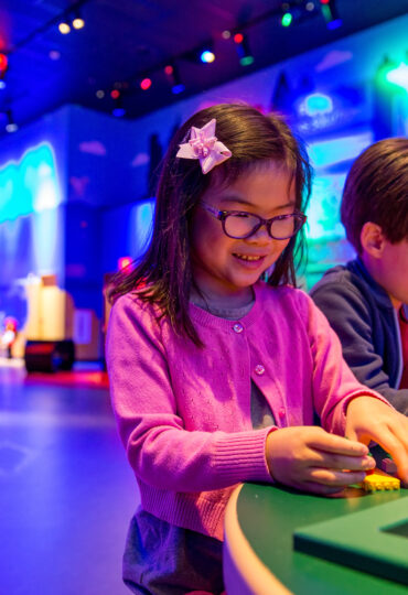 Two children play with an exhibit at a museum of science.