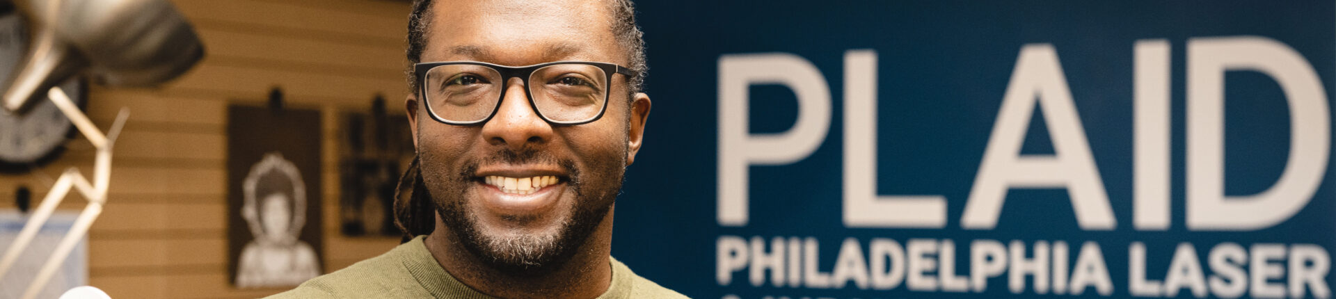 A man wearing glasses smiles at the camera.