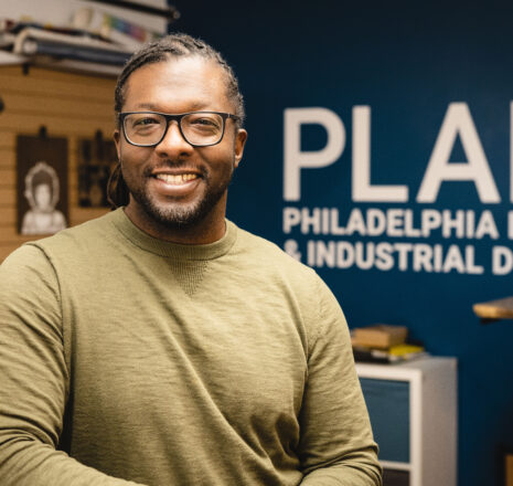 A man wearing glasses smiles at the camera.