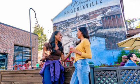 Two women chat in front of a sign that reads 