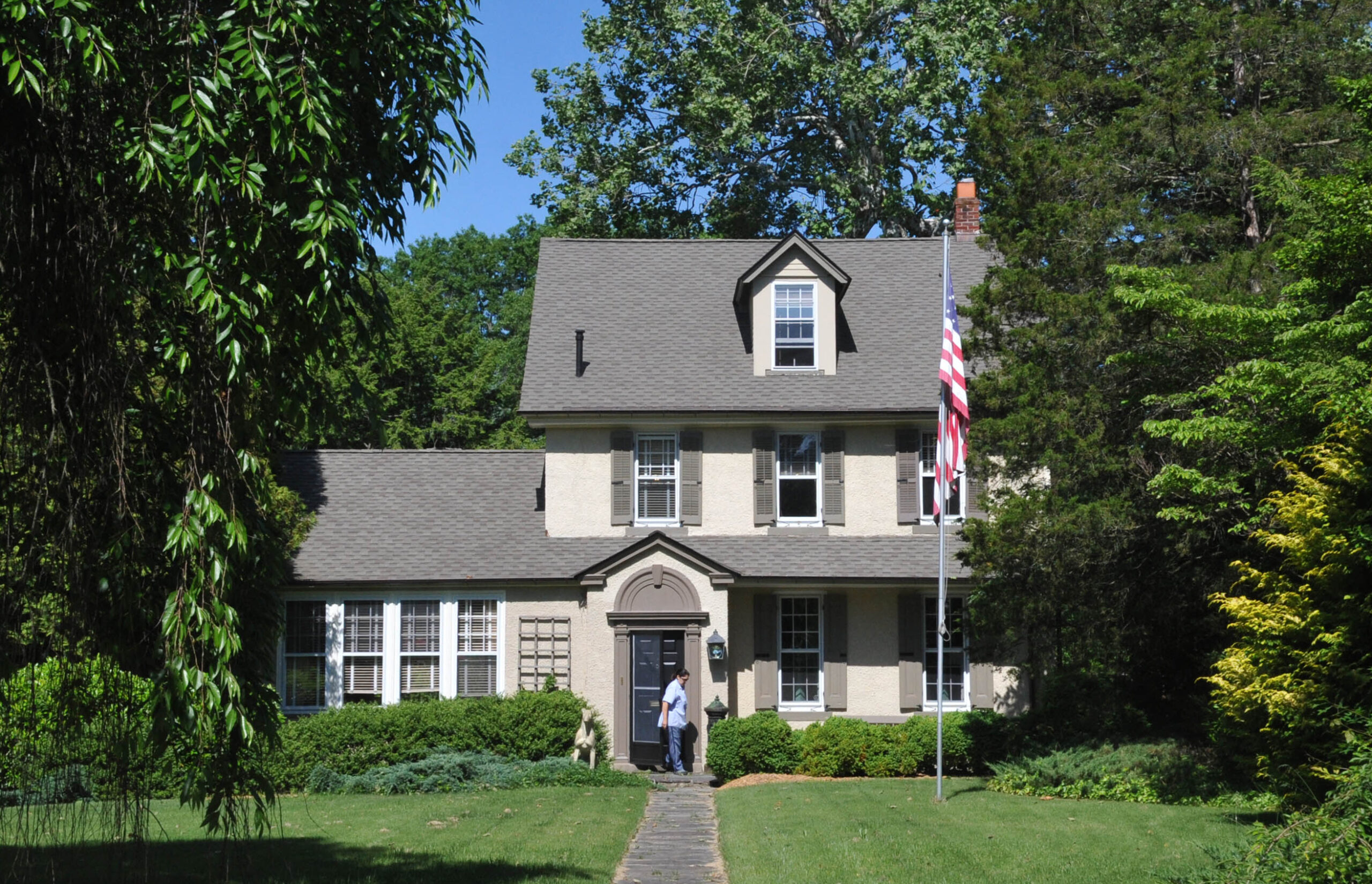 A gray, stone house with an American flag on a flagpool in the front yard.